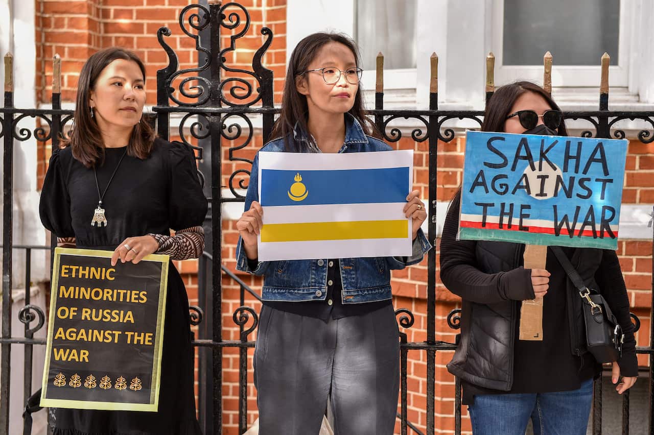 Three Asian women hold placards with anti-war slogans 