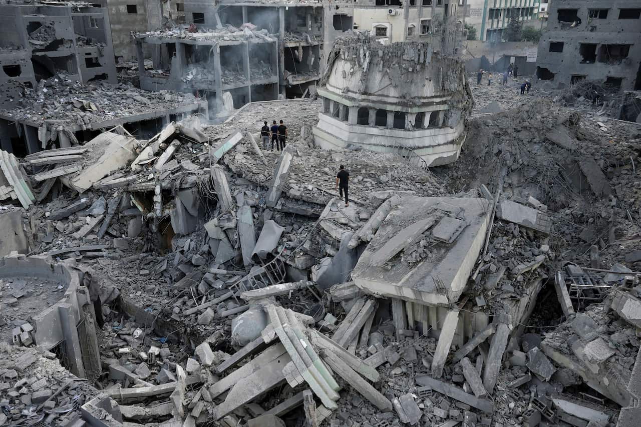 People stand in the ruins of damaged buildings
