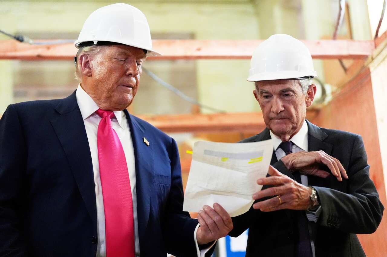 Two men wearing hard hats and suits looking at a piece of paper.
