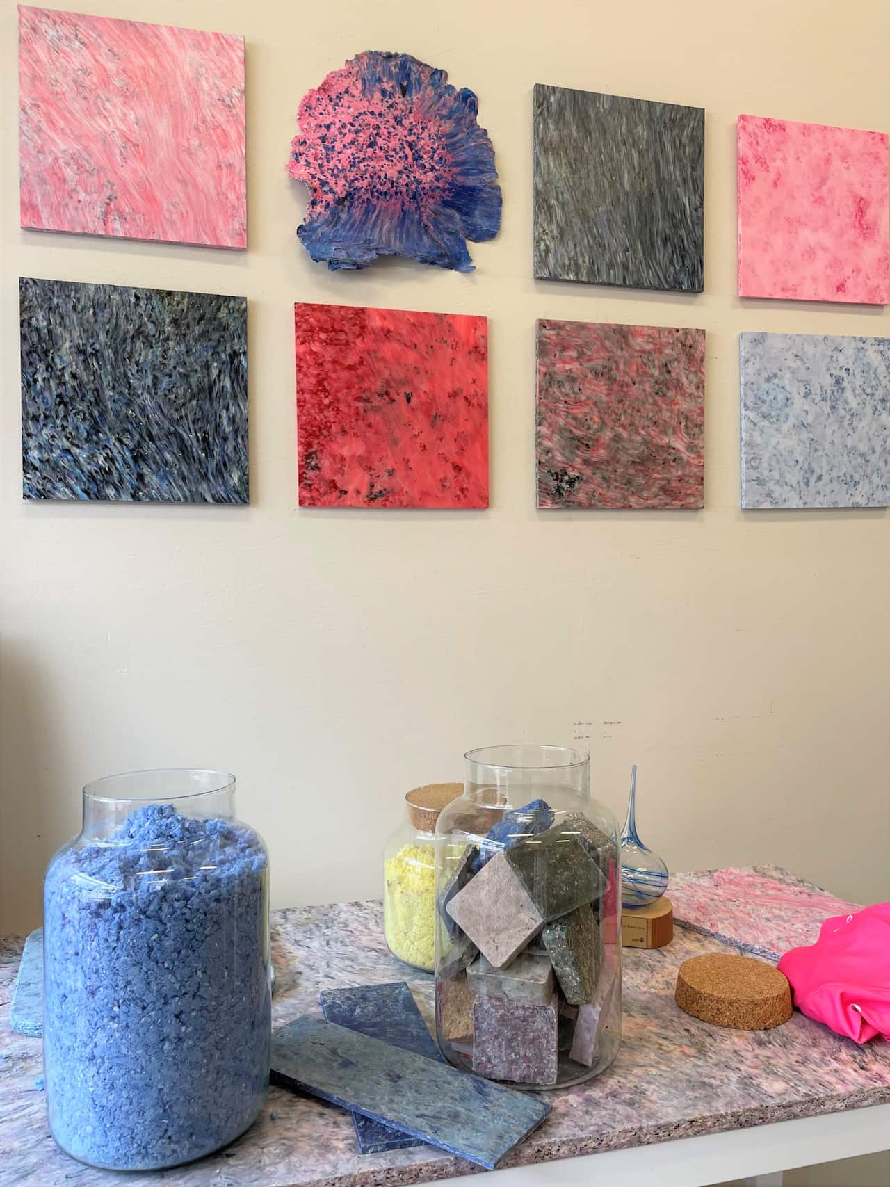A jar of fibres sits on a table in front of colourful panels.
