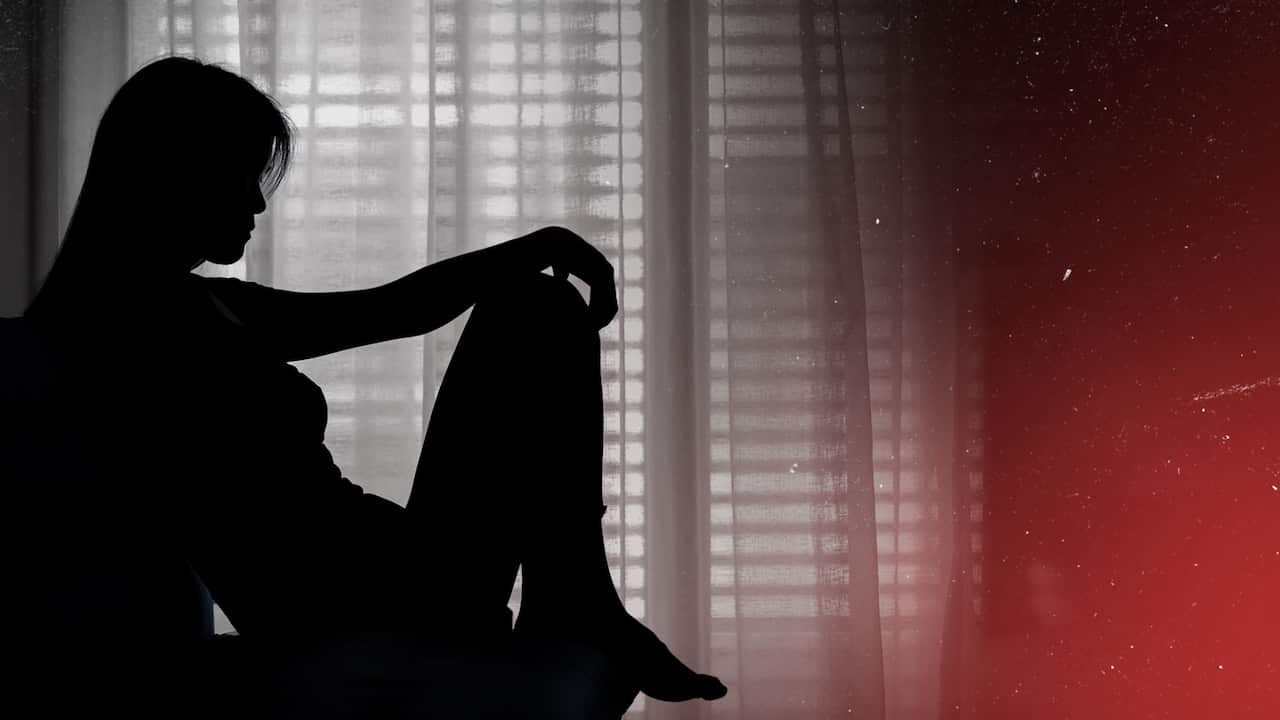 A woman, who is anonymous, sits by a window.