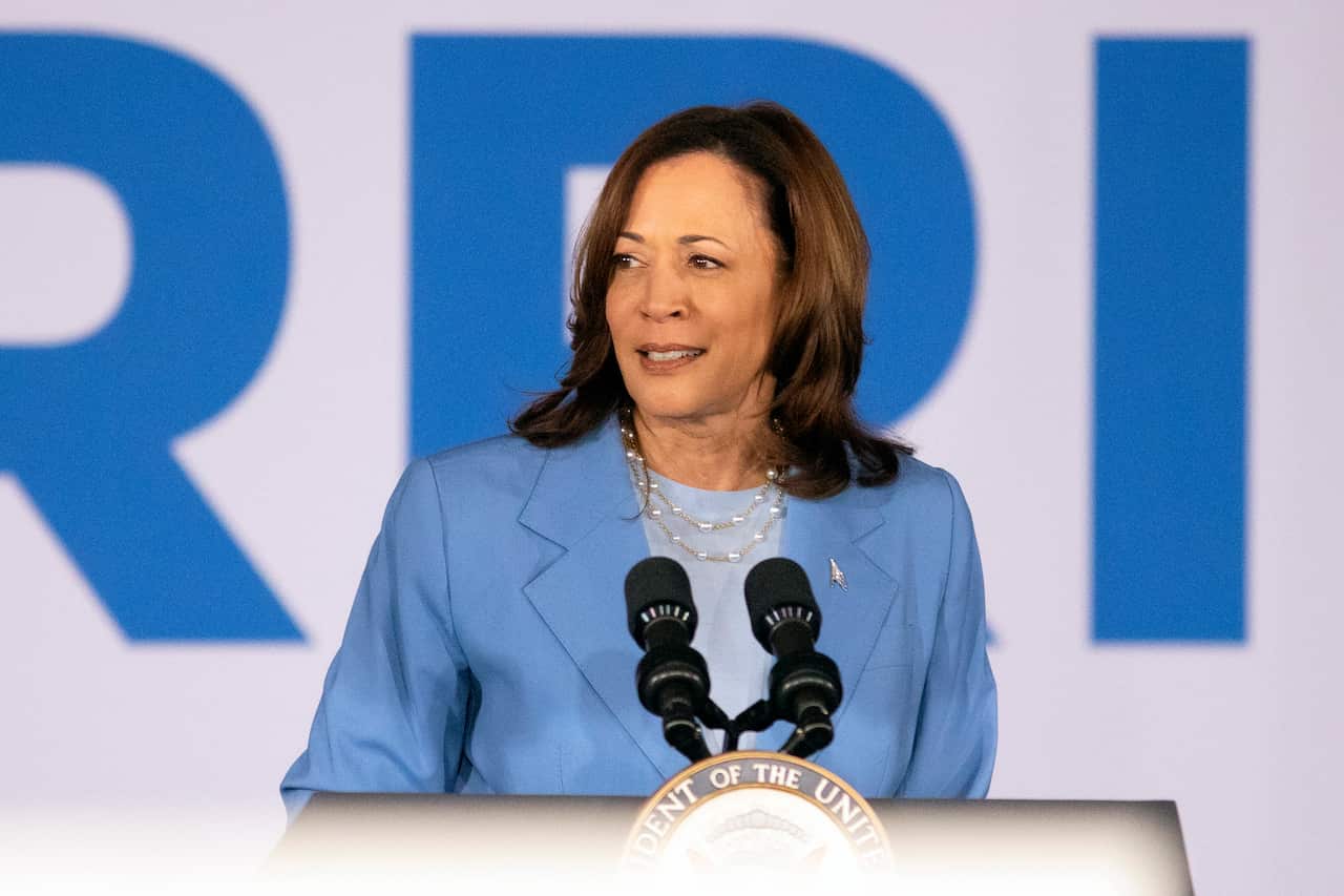 Kamala Harris in a blue blazer speaking into microphones on a podium.