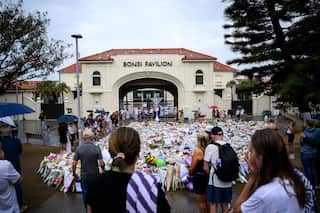 Flowers and other tributes on the ground outside Bondi Pavilion, where people are gathered.