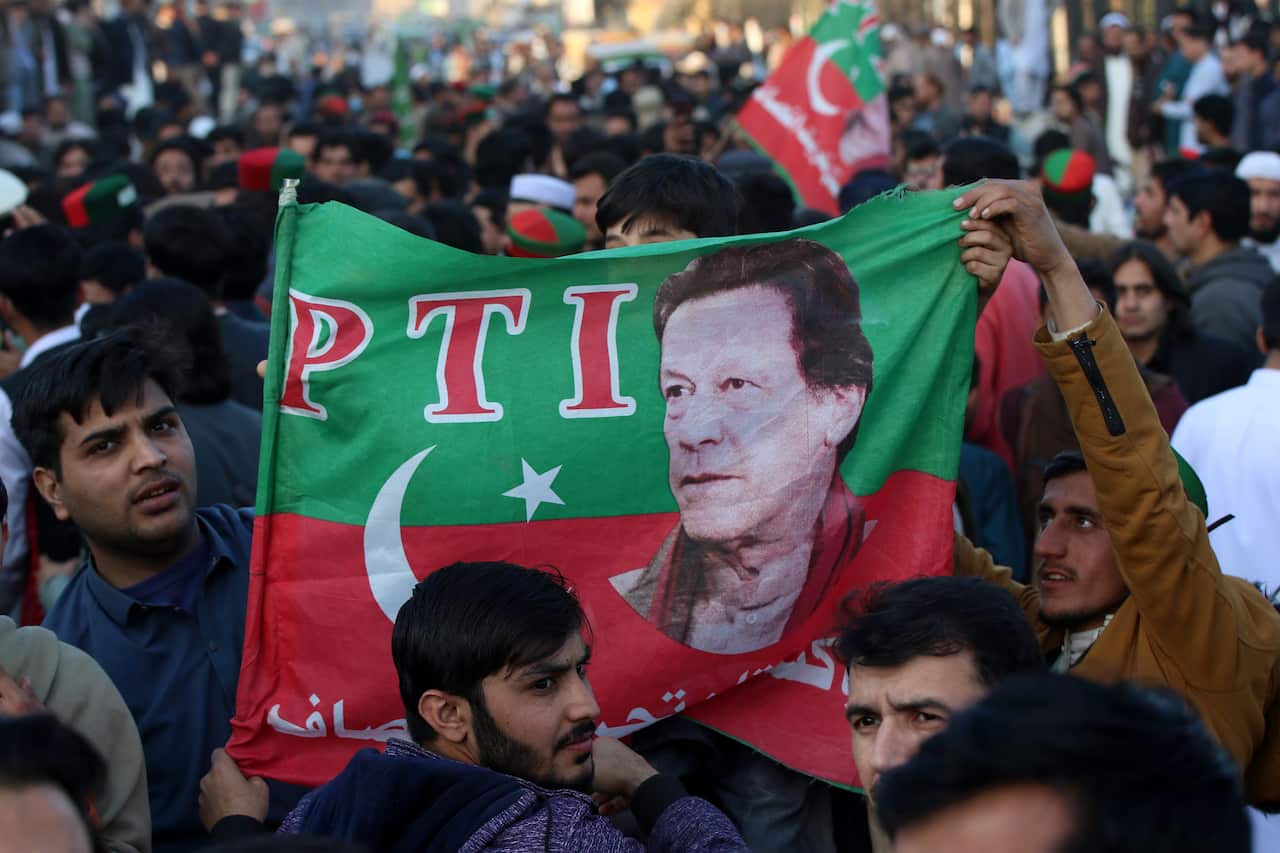 Men carry a Pakistani flag, with a politicians face on it.
