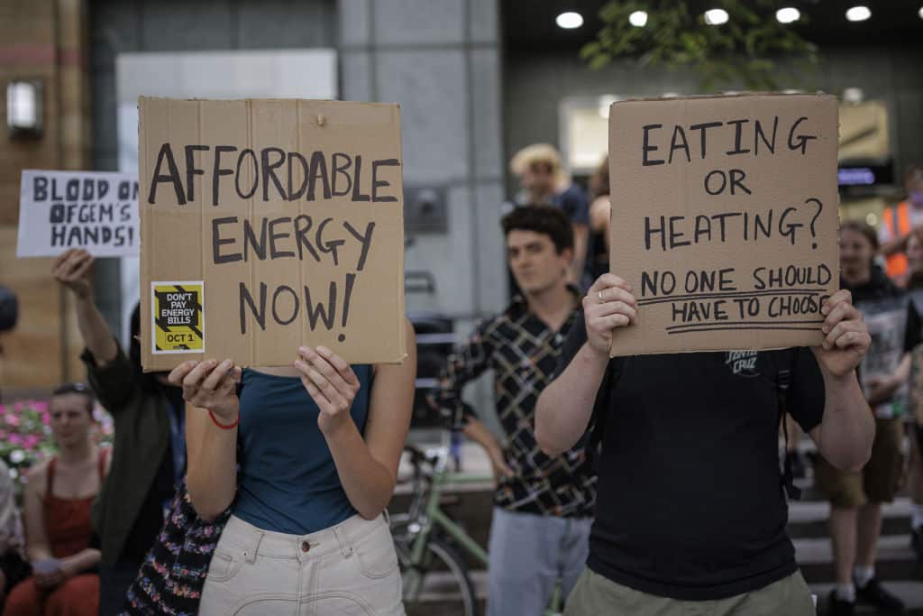 People hold placards at a protest against rising energy prices in UK 
