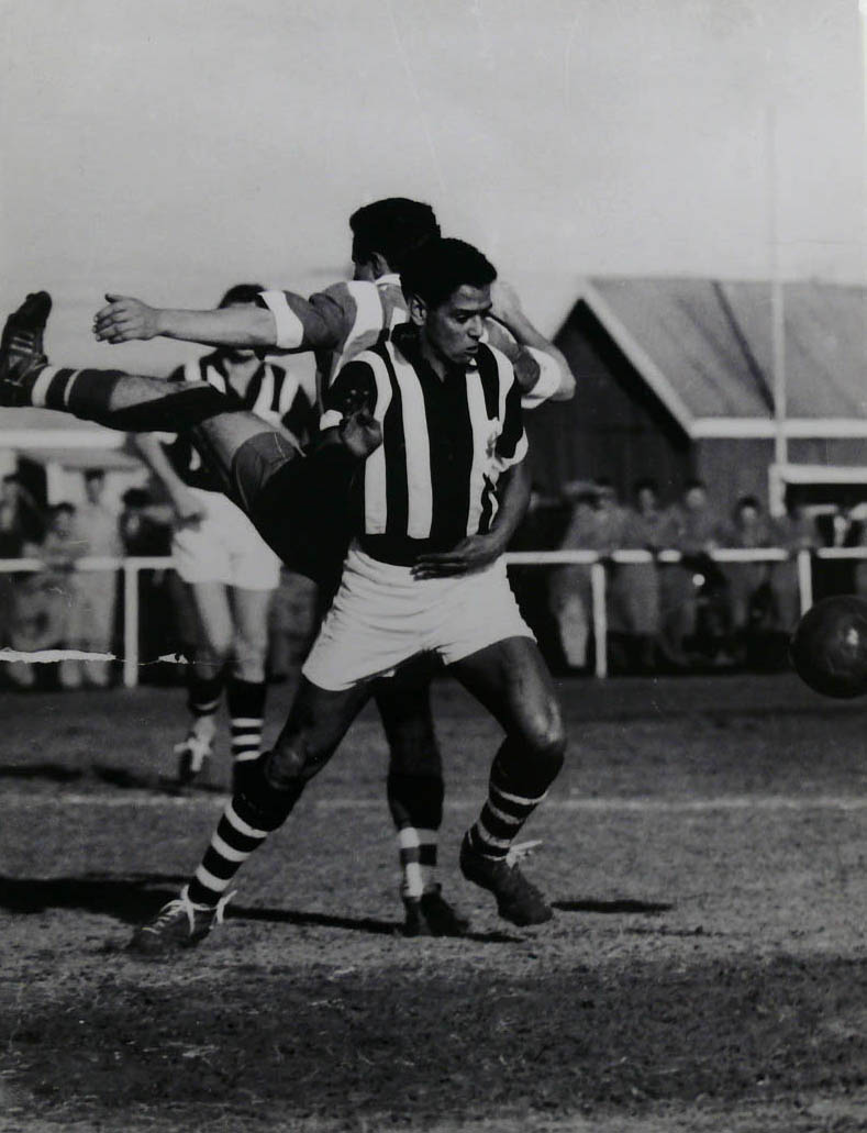 black-and-white image of two footballers in action. They are wearing striped jerseys.