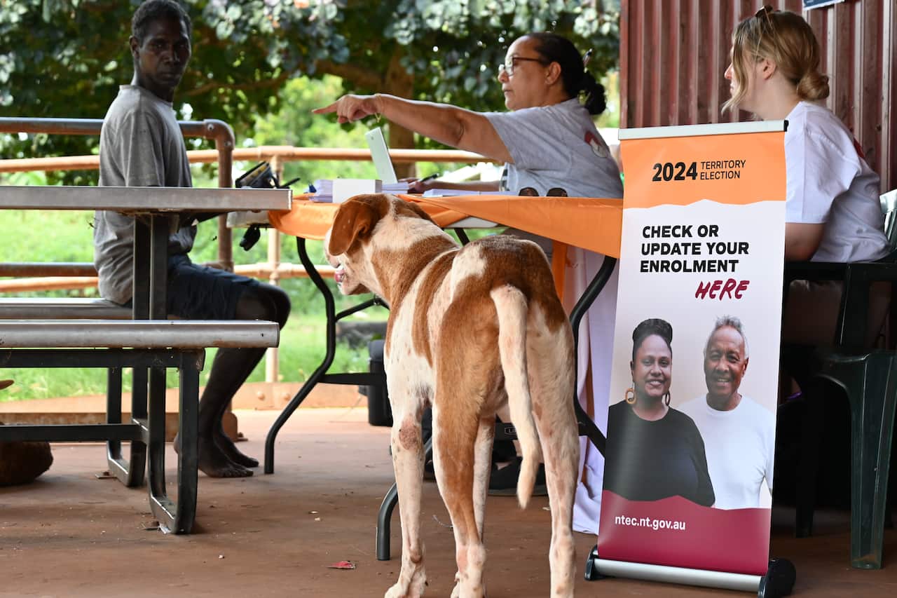 A Ramingining resident talks to Remote Engagement Officers at the Northern Territory Electoral Commission's pop-up stall out the front of the community's only store
