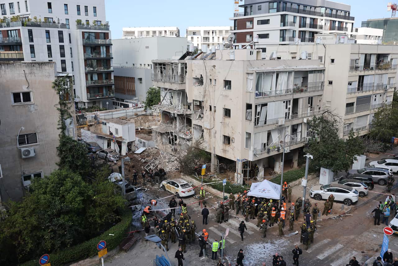 A large group of emergency workers near a bombed-out site in a city.
