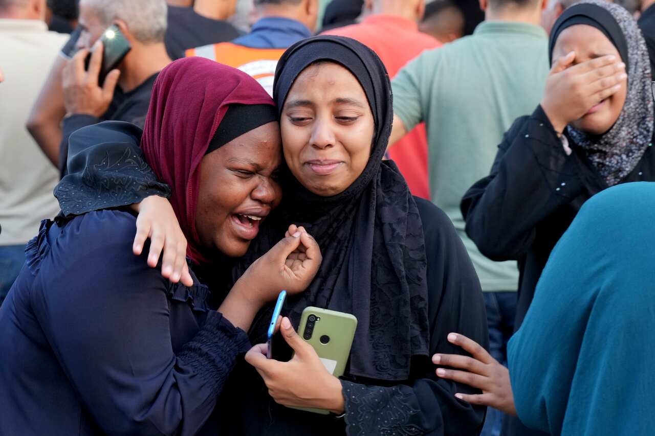 Two women crying. The one on the right has her arm around the other.