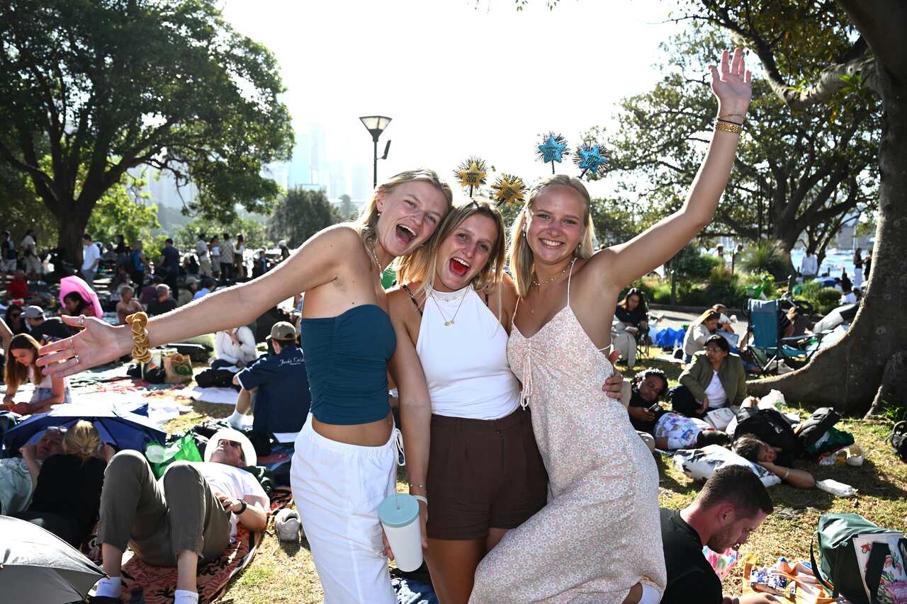 Three women pose for photographs as they smile 