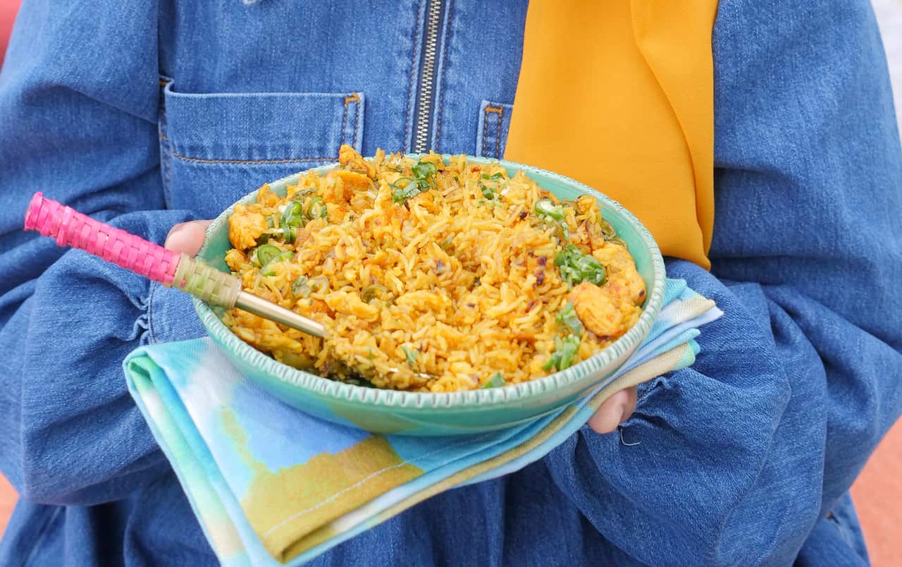 A green dish holds a yellow-toned rice dish. 