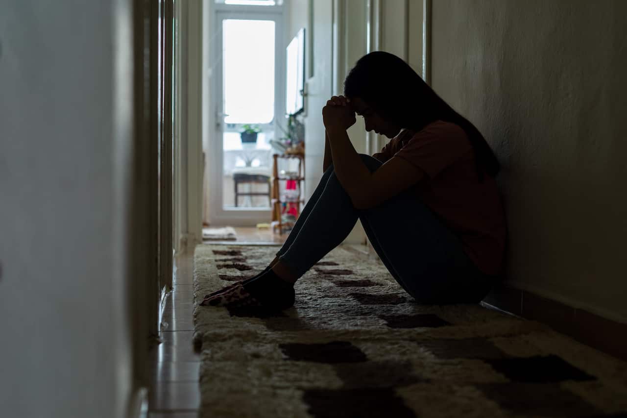 Sad woman sitting corridor floor