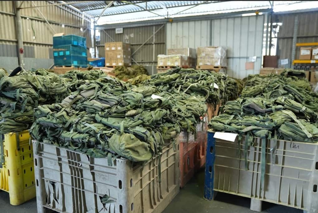 Large crates full of army backpacks in a warehouse.