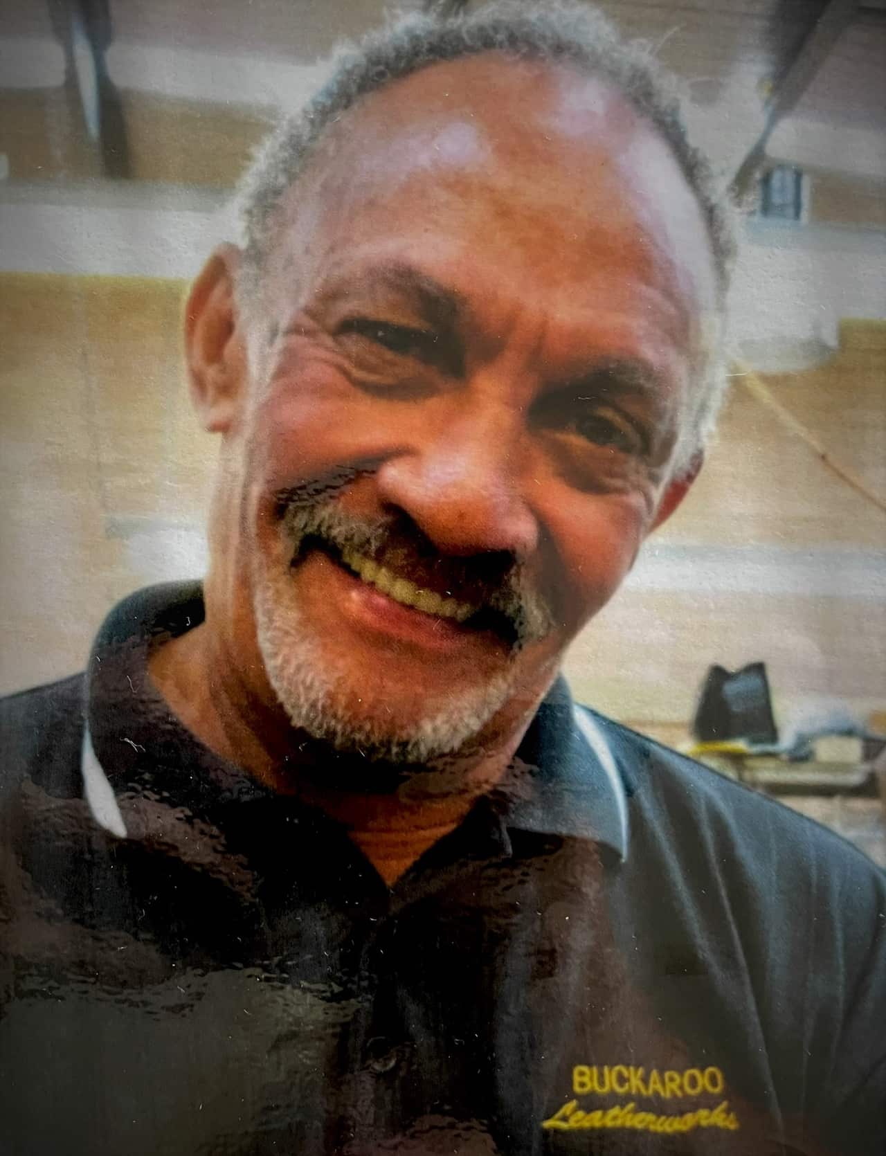 A man in a black t-shirt smiles at camera.