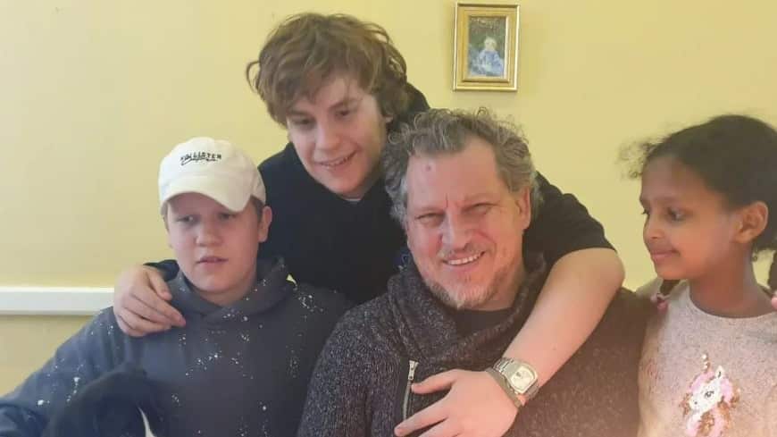 A man, two teenage boys and a young girl sitting at a table