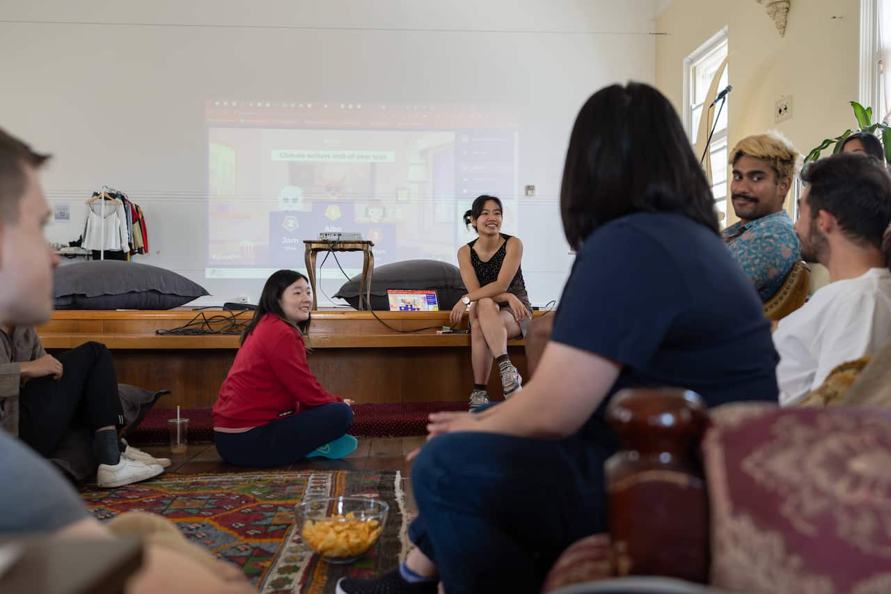 A group of people sit on sofas around a small stage