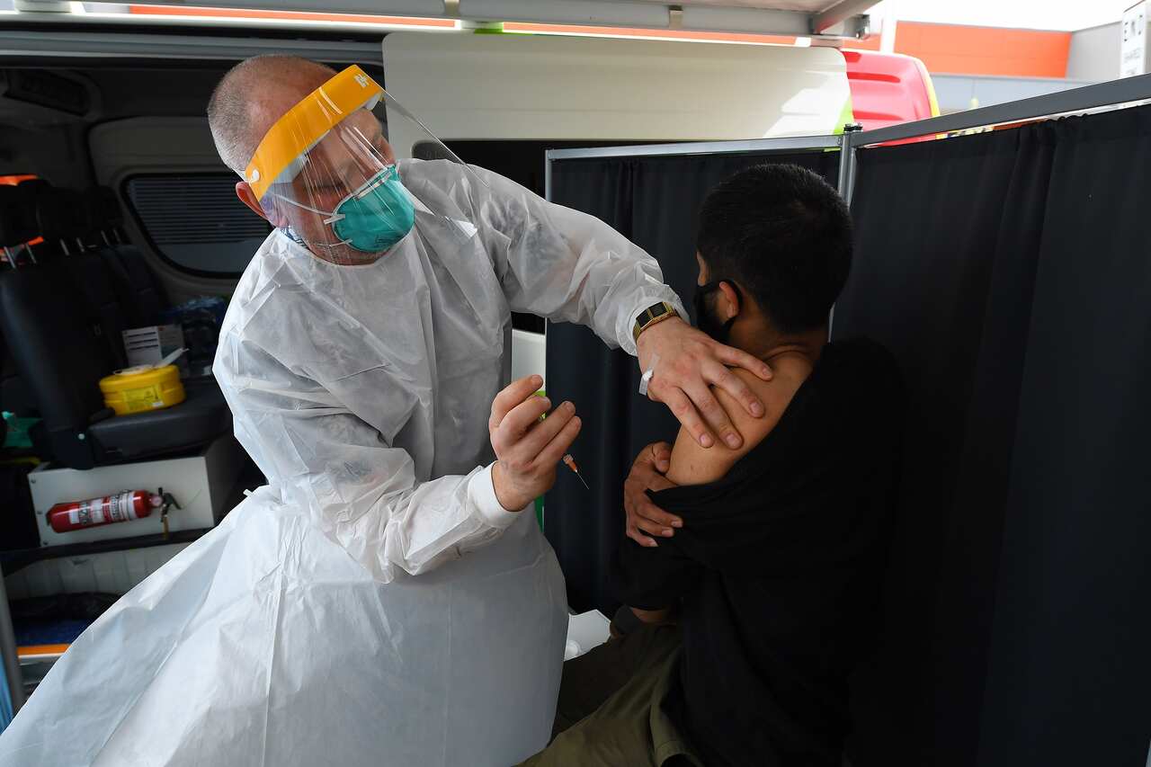 A healthcare working administering a COVID-19 vaccine into a person's arm.