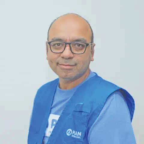 A man wearing a blue humanitarian aid vest.