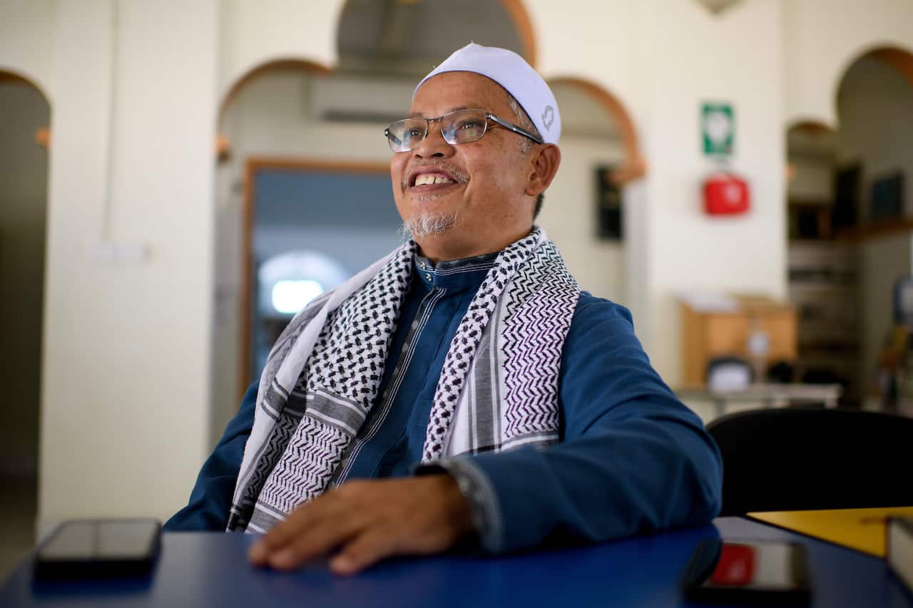 A man speaking while seated indoors.