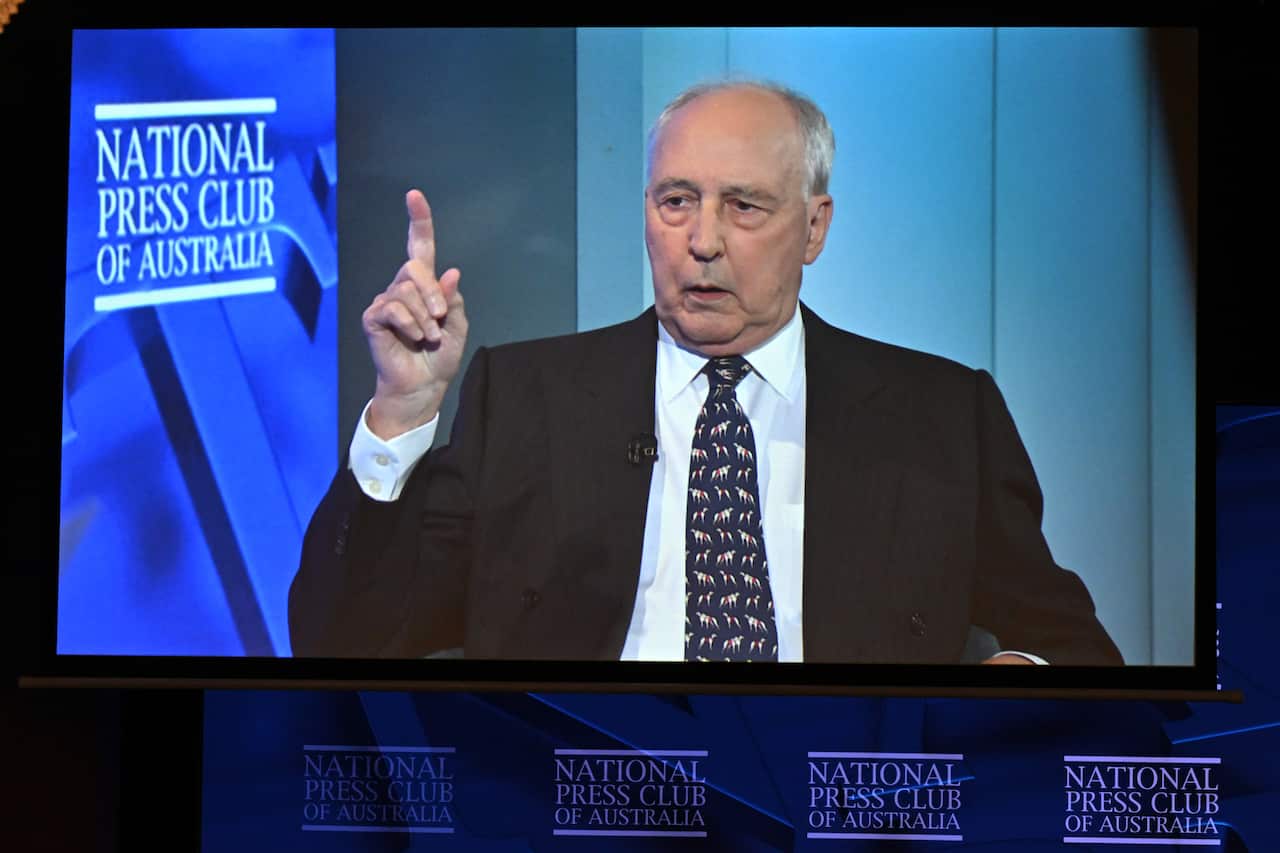 A man speaking in front of a blue background