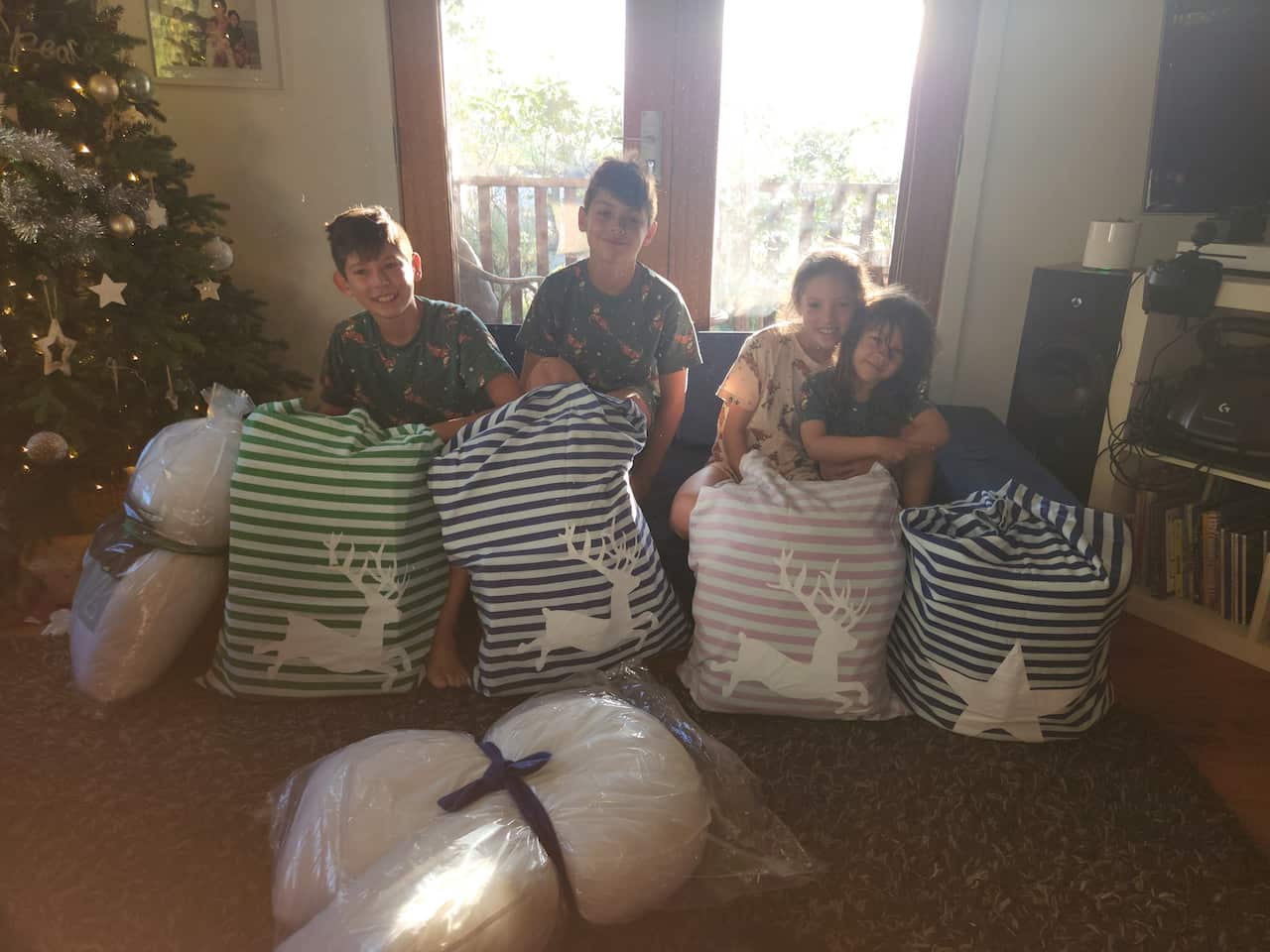 Four children on Christmas day sitting eagerly waiting to open their presents