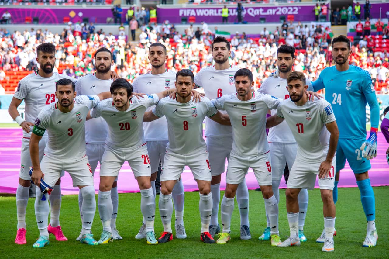 A team of white-jersey-wearing men pose for a photo. 