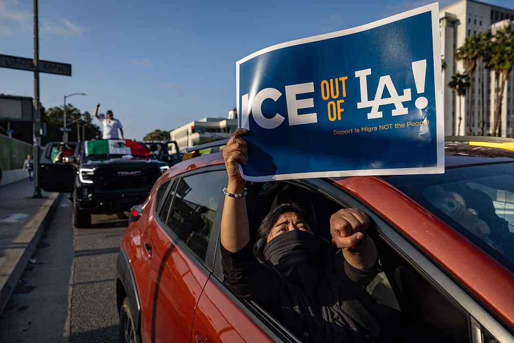 A protester holds a sign from inside a car. 