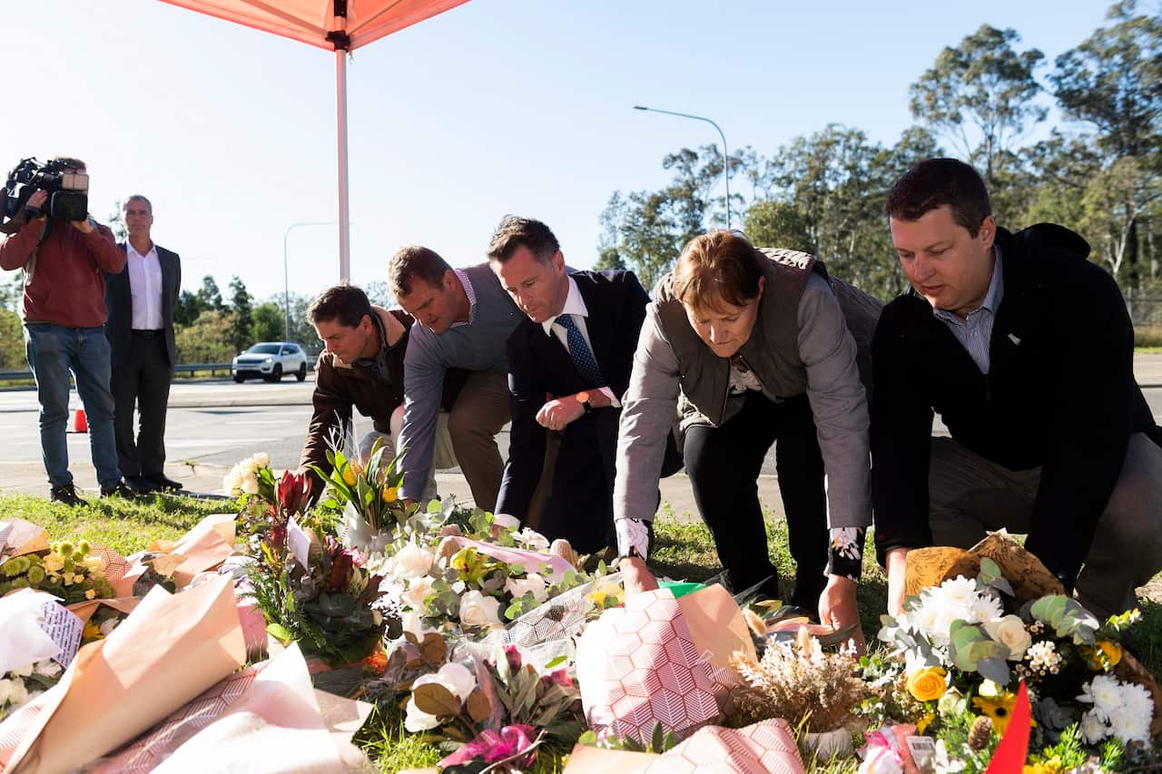 NSW Premier Chris Minns joins others in adding flowers to a makeshift memorial at a crash site.