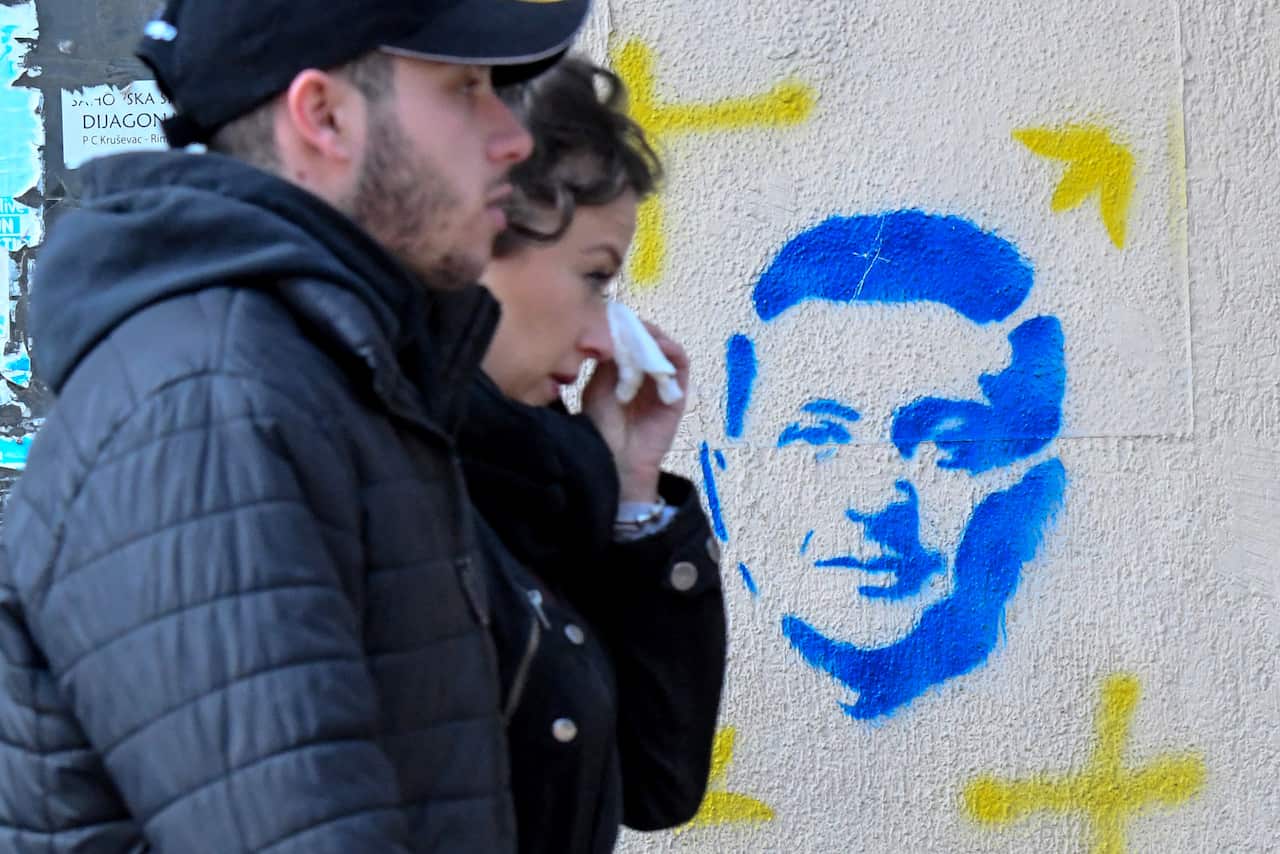 People walk past a stencil painting depicting Ukraine's President Volodymyr Zelenskyy on a building in downtown Podgorica, Montenegro in 2022.