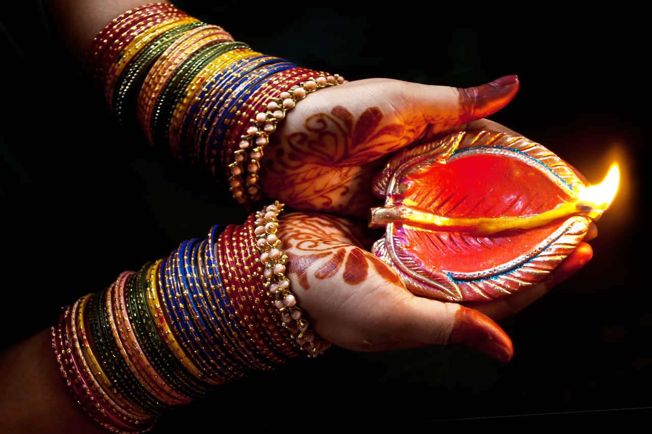 Woman with lit earthen lamp at Diwali festival