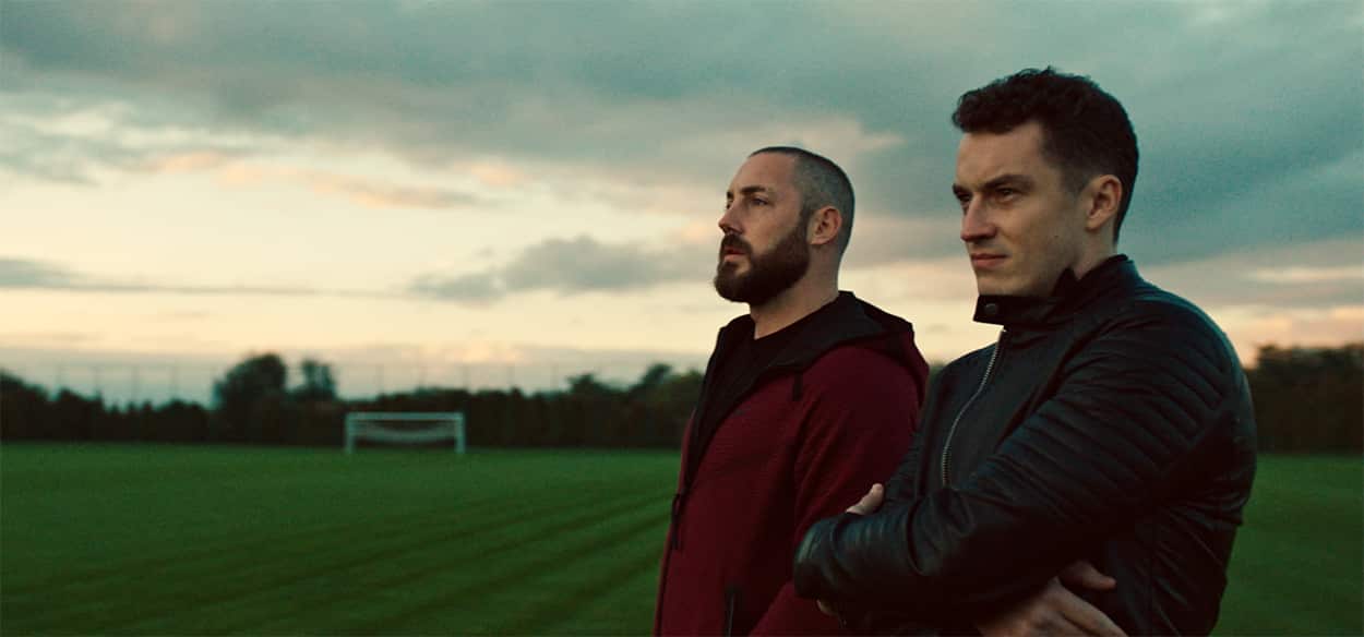 Two men stand on a soccer field close to sunset.jpg