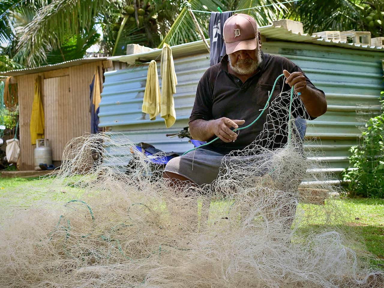 A fisherman untangles his net. 