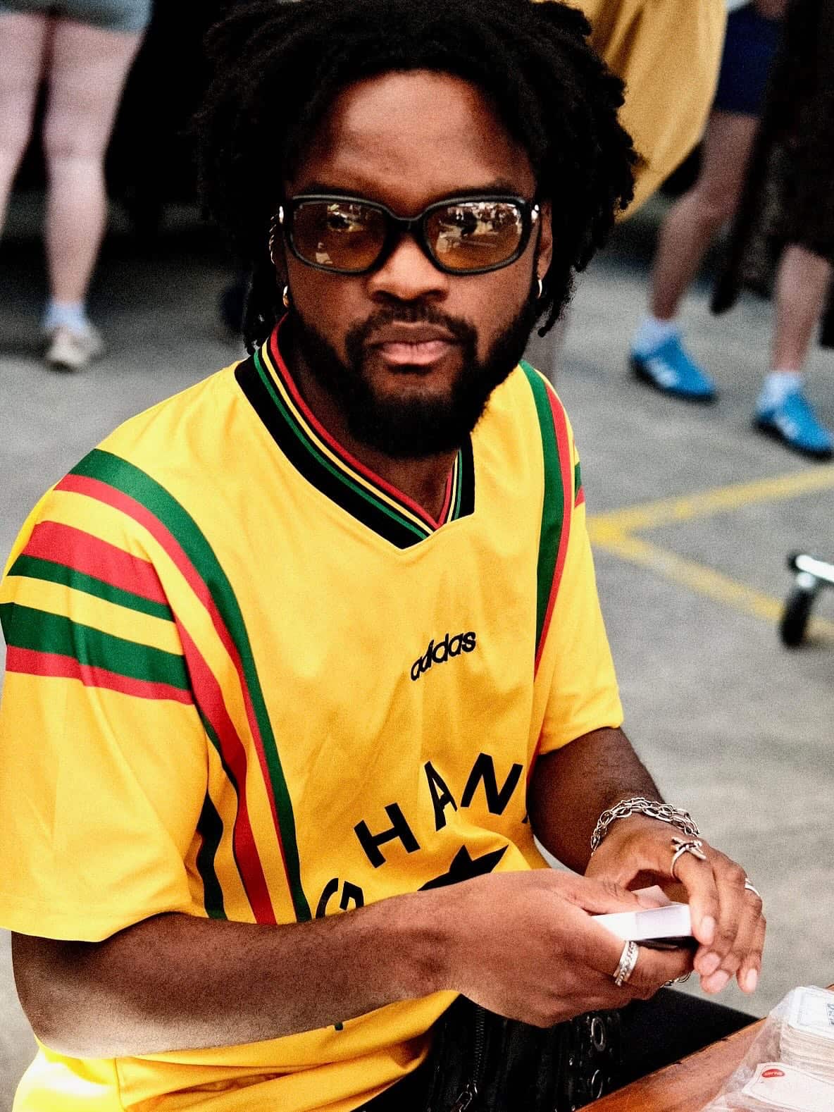 A man is wearing a yellow Ghana shirt while holding UNO cards 