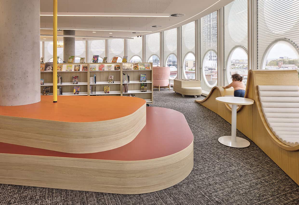 The interior of a library. A child is climbing one of the lounges.