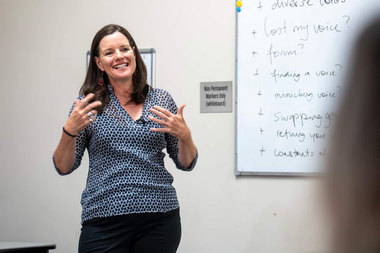 A woman delivering a presentation in front of a whiteboard.