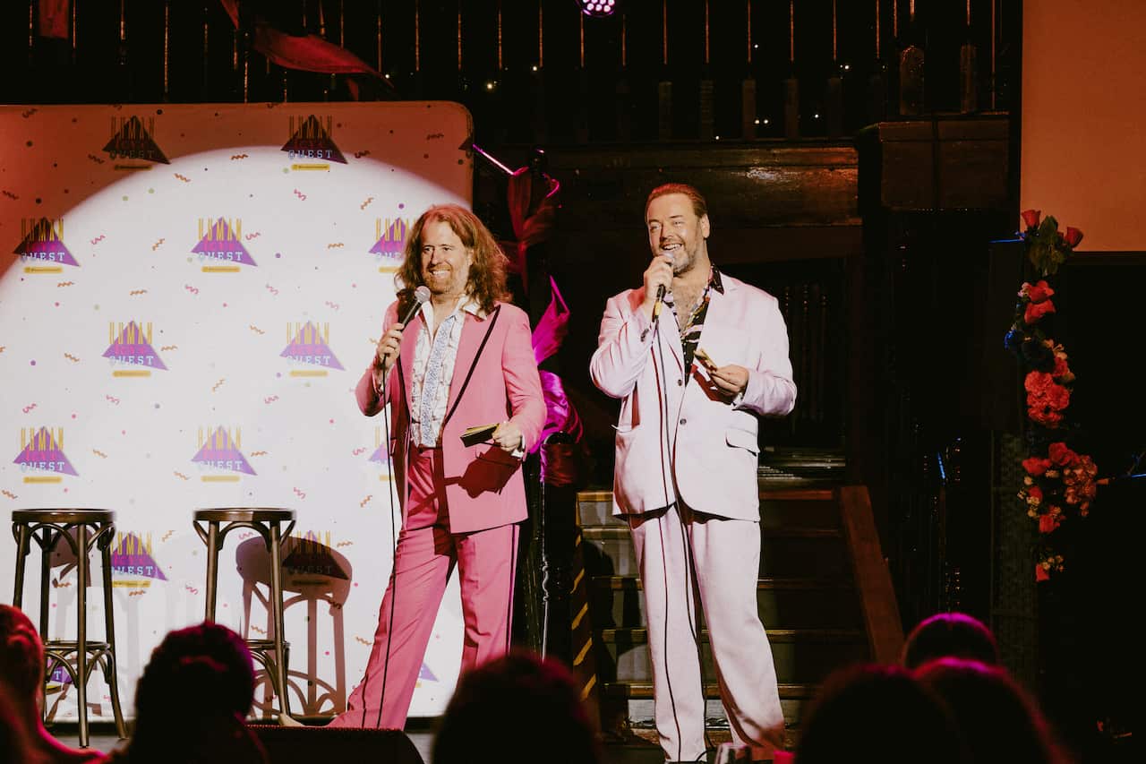 Two men wearing retro suits on stage.