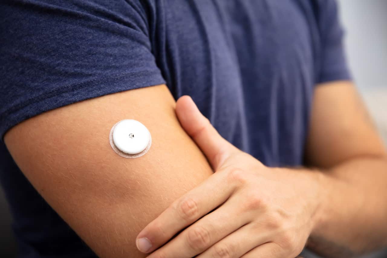 A white circular device on a man's arm.