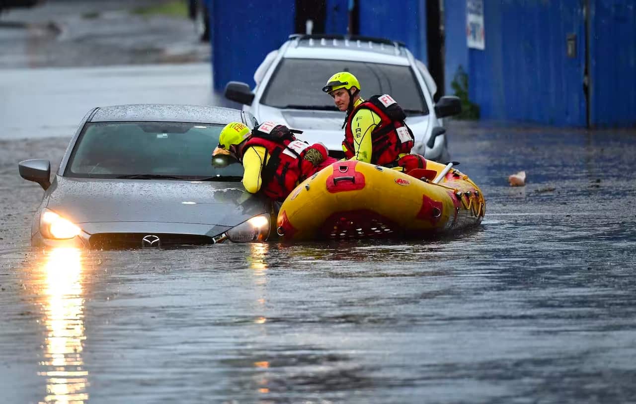Rescuers in a boat in a flood next to a car.