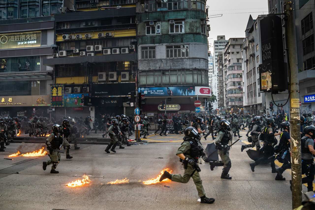 Riot police officers rush forward to arrest protesters as they were being attacked by the protesters by petrol bombs.