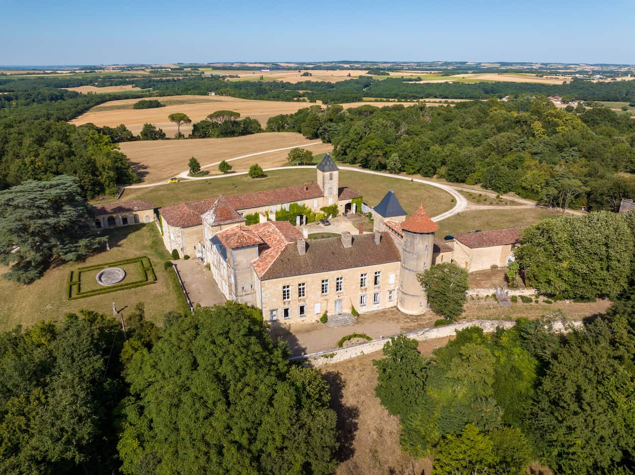 An aerial shot of a manor house in the French countryside. It was multiple buildings, including towers. 