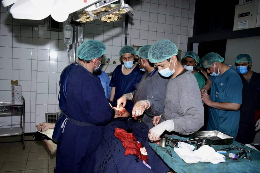 Health workers standing around an operating table with a man on it.