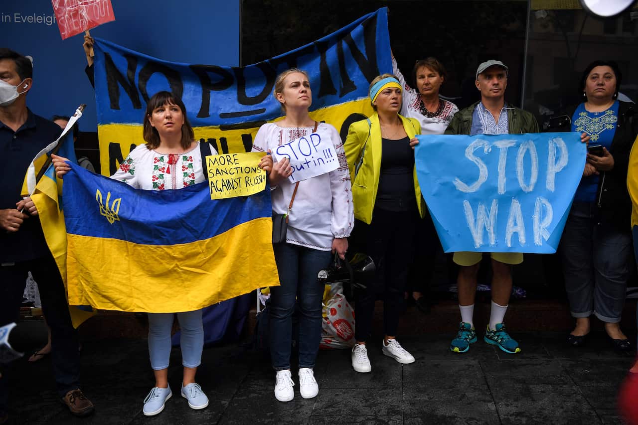 Protesters hold placards and Ukrainian flags during a rally at Martin Place in Sydney, Friday, 25 February, 2022.