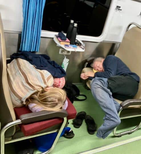 Theo Simon and his daughter Rosa sleeping sideways on train seats.
