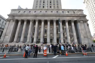 A neo-classical style court building in New York with people gathered outside.