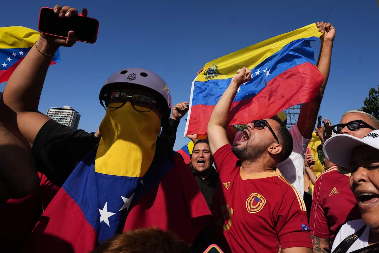 A gorup of people holding the Venezuelan flag celebrate