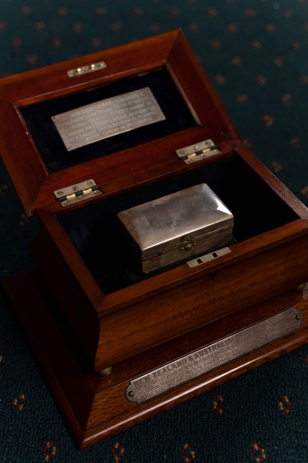 An opened wooden box with a smaller metal box inside it