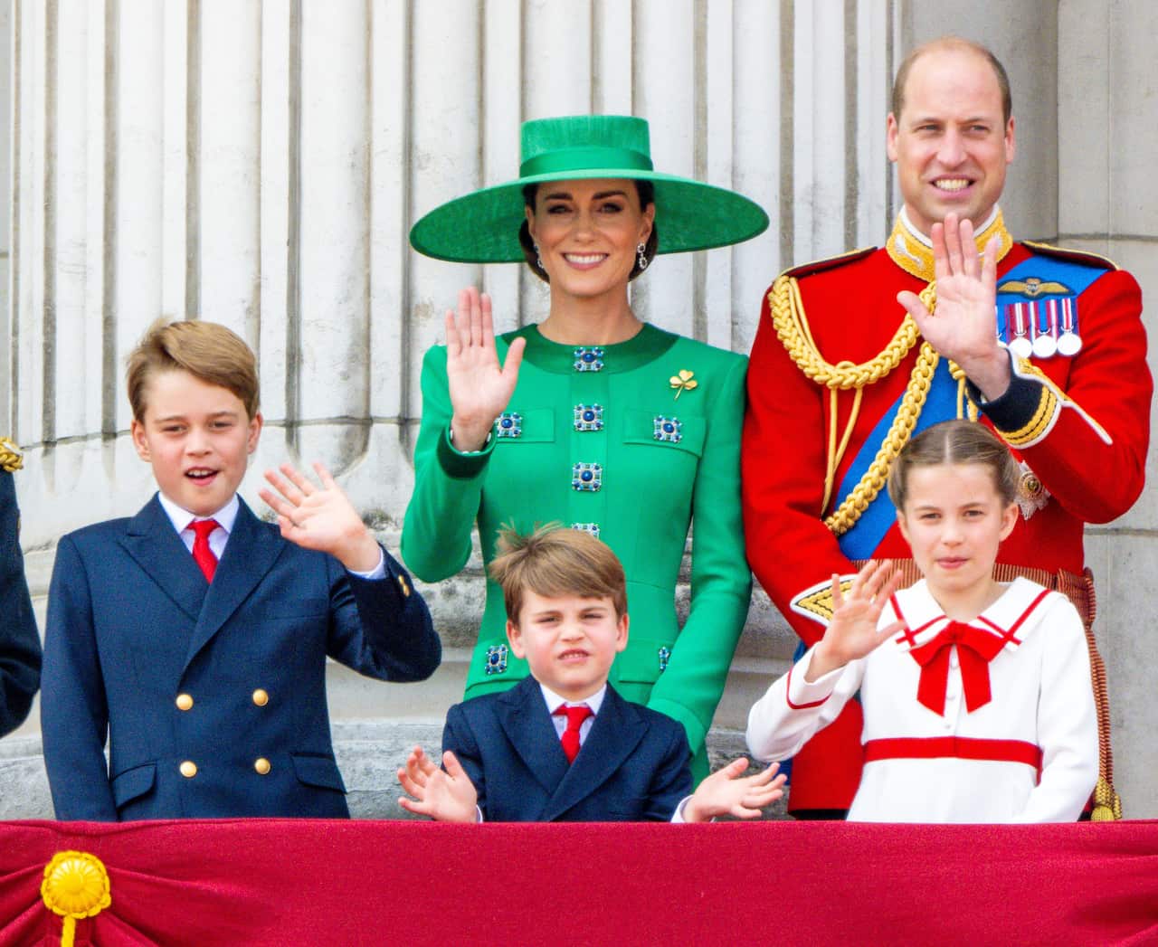 Two adults and three children waving.