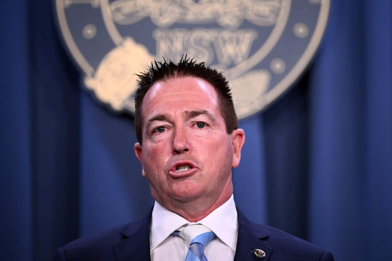 A man wearing a suit and tie who is speaking.