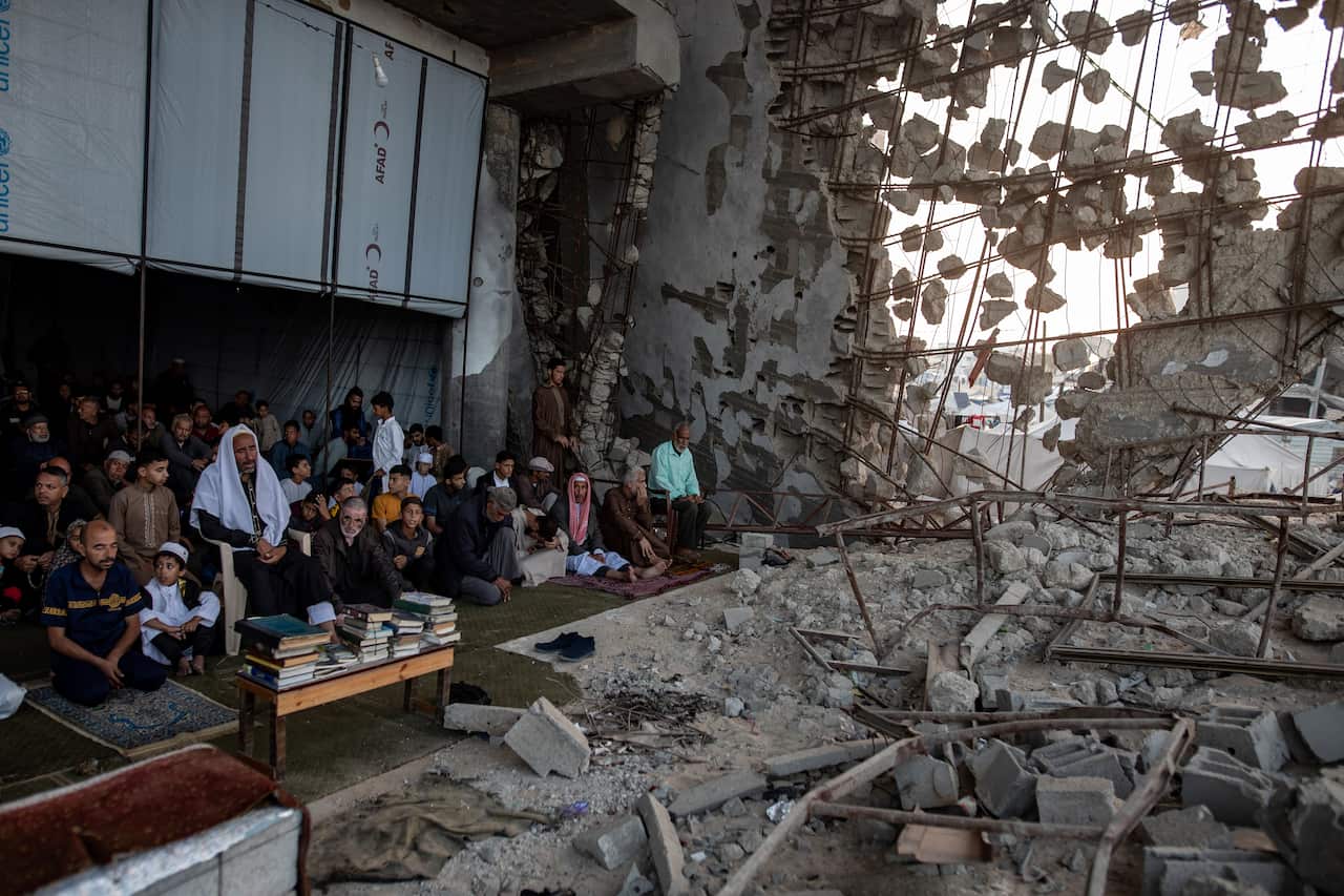 A group of Palestinians perform Eid al-Adha prayers in the ruins of a destroyed mosque