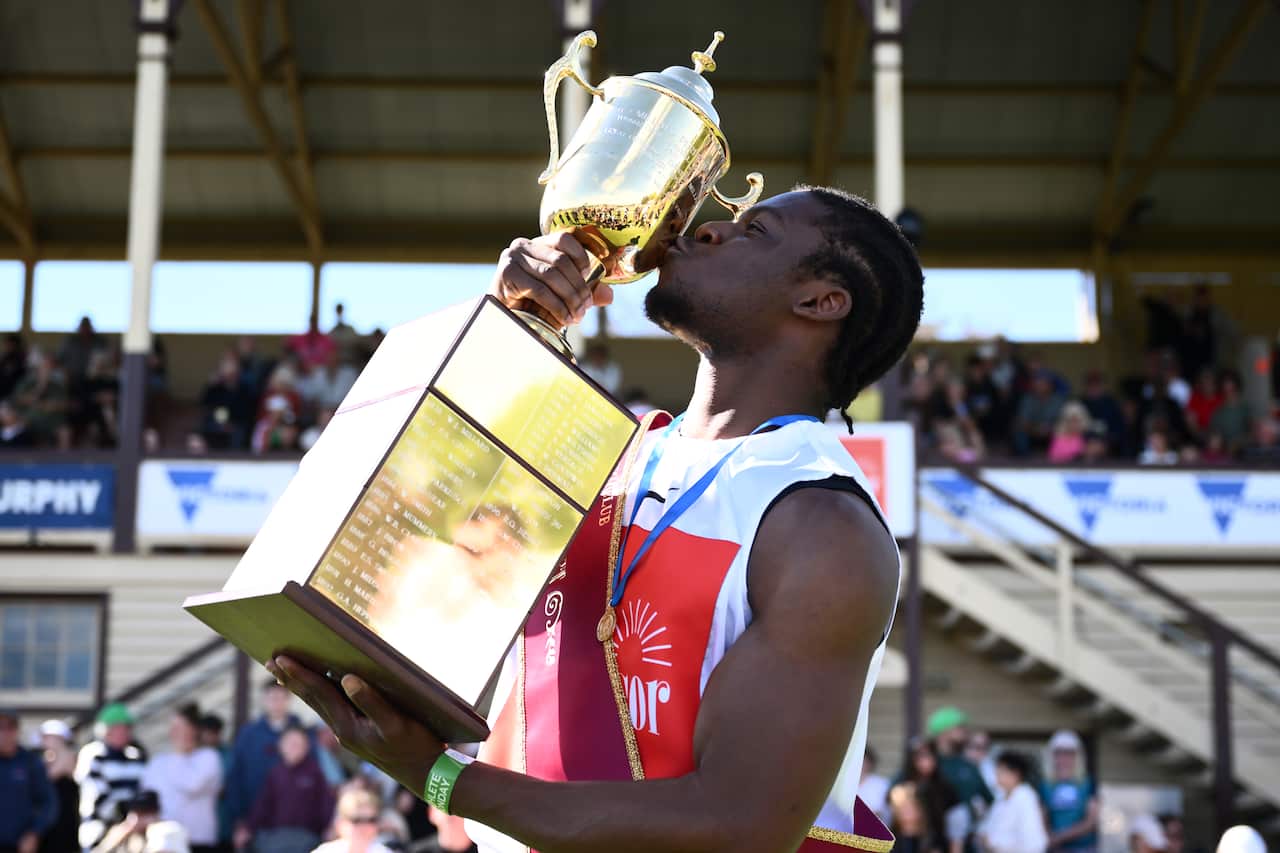 A man holding up a golden trophy.